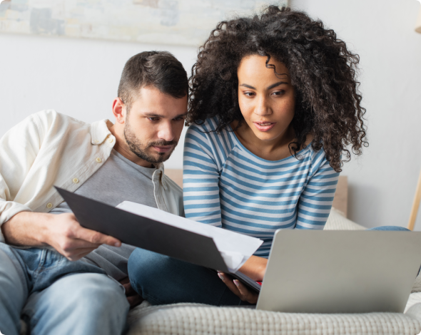 a man and woman looking at papers and a laptop