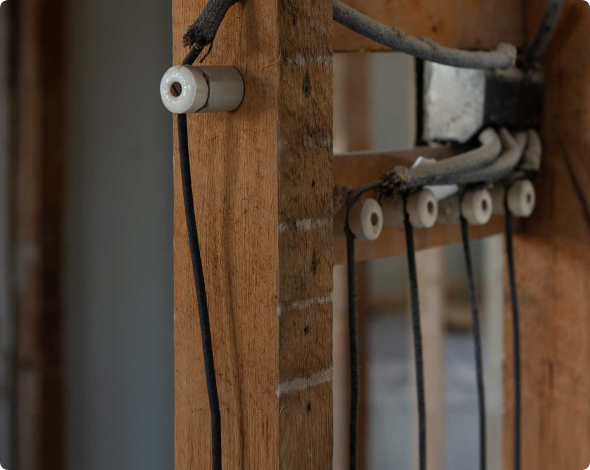 Image of exposed knob and tube wiring within the framing of a home's wall.