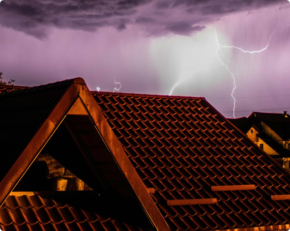 Silhouette of roofs with lightning in purple sky.