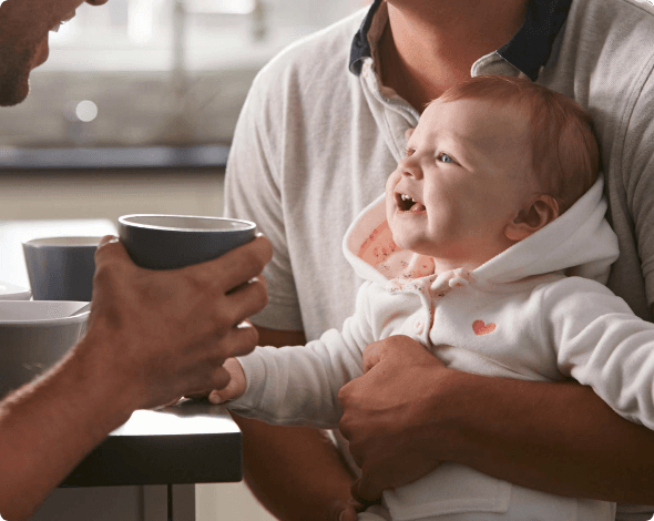 Image of fathers with their baby - playing in the kitchen.